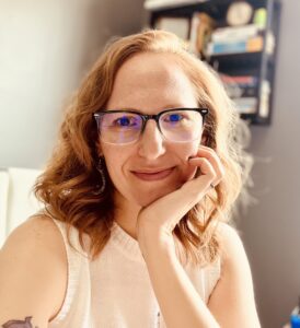 Katie Bingner, licensed counselor and communication coach in Maryland, chin resting in palm, smiling with glasses.